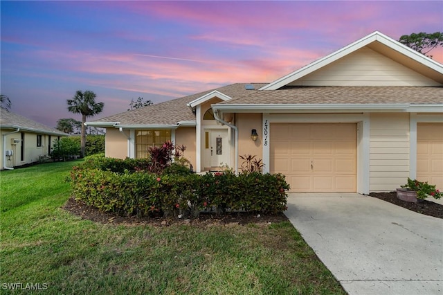 single story home featuring a garage and a lawn