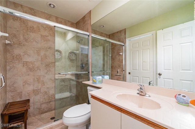 bathroom featuring vanity, toilet, and a shower with door