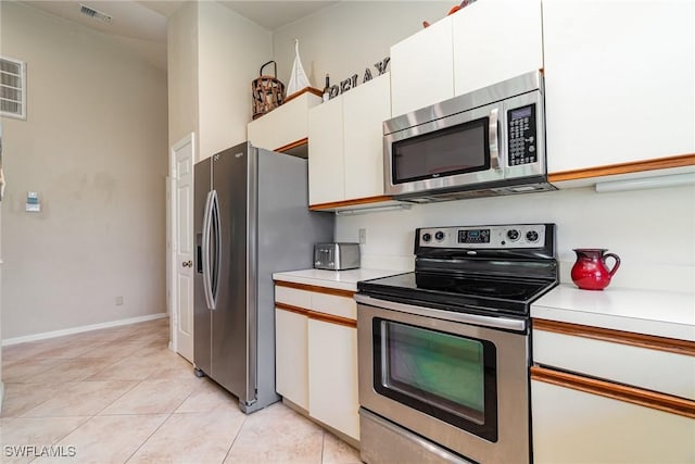 kitchen with light tile patterned flooring, stainless steel appliances, and white cabinets