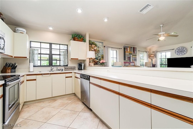 kitchen with white cabinetry, light tile patterned floors, kitchen peninsula, a wealth of natural light, and stainless steel appliances