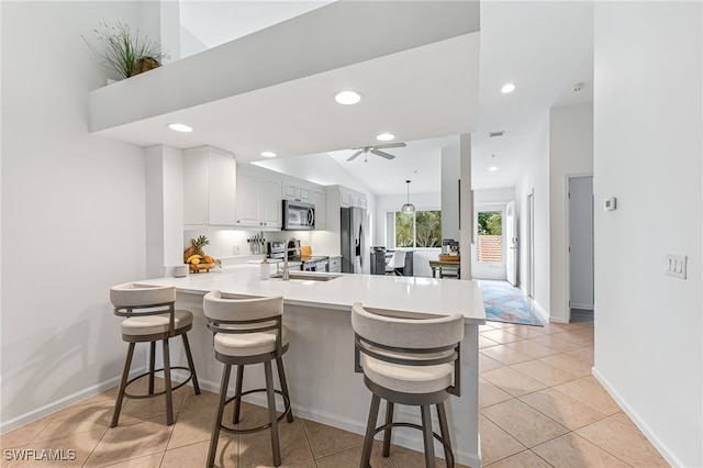 kitchen with a peninsula, a breakfast bar, white cabinets, light countertops, and appliances with stainless steel finishes