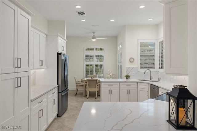 kitchen featuring sink, appliances with stainless steel finishes, ceiling fan, light stone countertops, and white cabinets