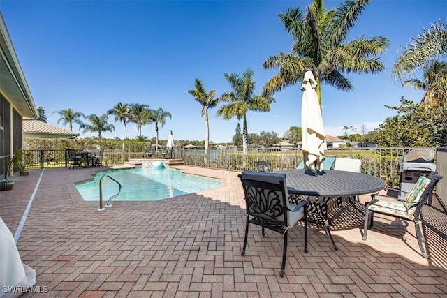 view of swimming pool featuring pool water feature, a grill, and a patio area