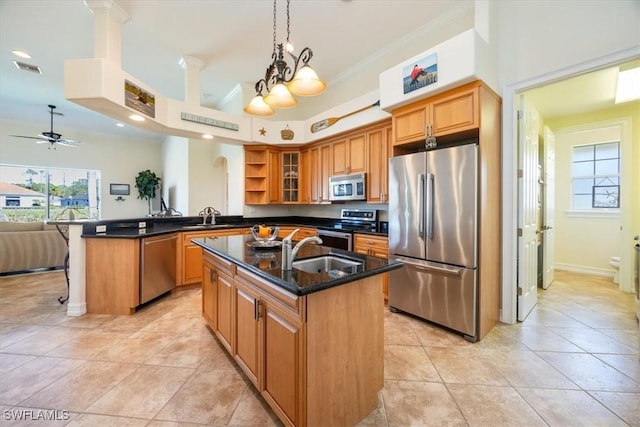 kitchen with appliances with stainless steel finishes, sink, kitchen peninsula, and an island with sink