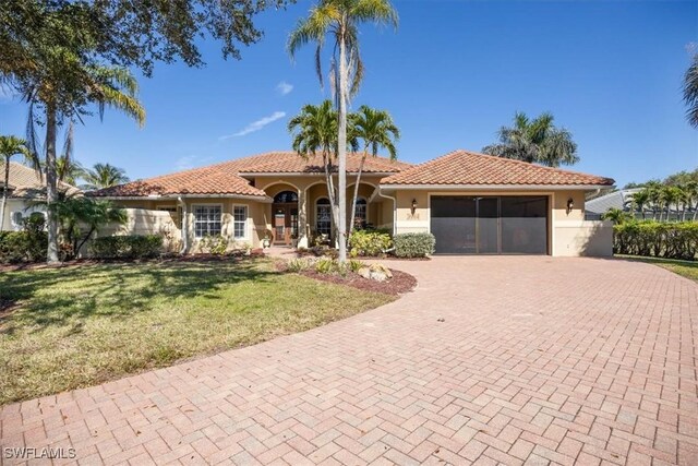 mediterranean / spanish-style house featuring a garage and a front yard