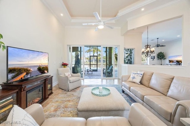 living room featuring a raised ceiling, crown molding, a towering ceiling, and ceiling fan with notable chandelier