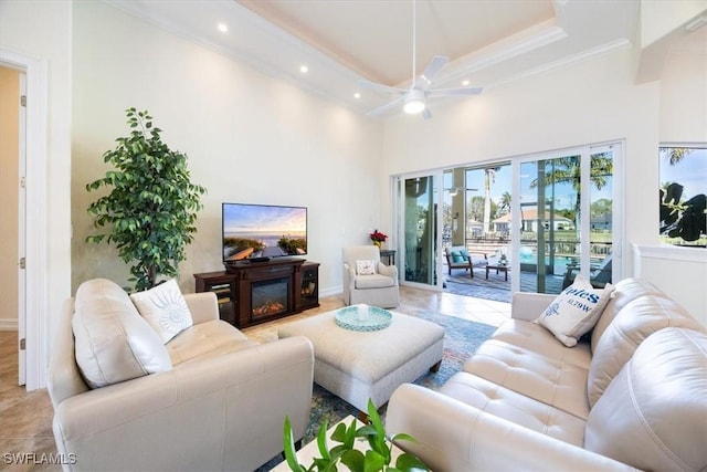 living room featuring light tile patterned floors, crown molding, ceiling fan, and a high ceiling