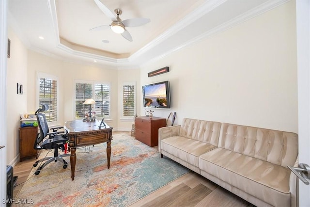 office area featuring a raised ceiling, ornamental molding, hardwood / wood-style flooring, and ceiling fan