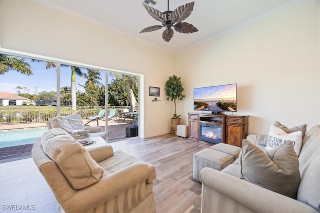 living room with ornamental molding, ceiling fan, and light wood-type flooring