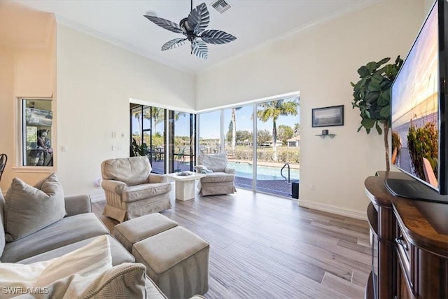 living room featuring ornamental molding, ceiling fan, and light wood-type flooring