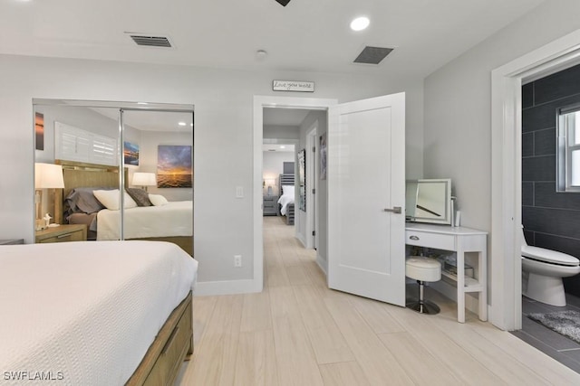 bedroom featuring light hardwood / wood-style floors, ensuite bathroom, and a closet