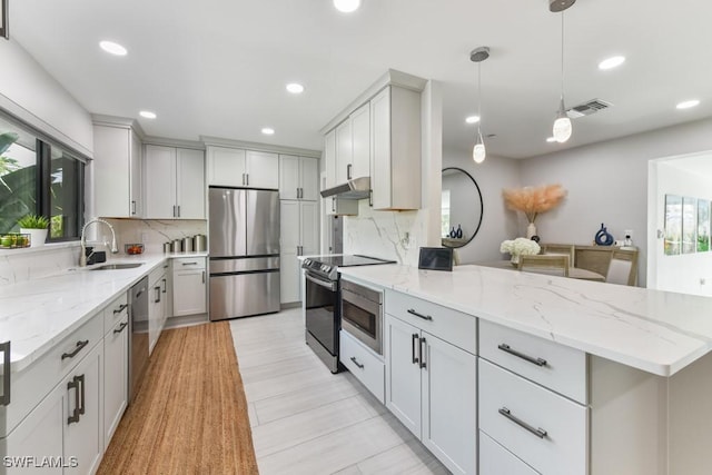 kitchen featuring sink, hanging light fixtures, stainless steel appliances, and tasteful backsplash