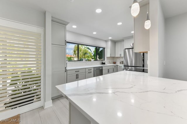 kitchen featuring appliances with stainless steel finishes, decorative light fixtures, gray cabinetry, light stone countertops, and decorative backsplash