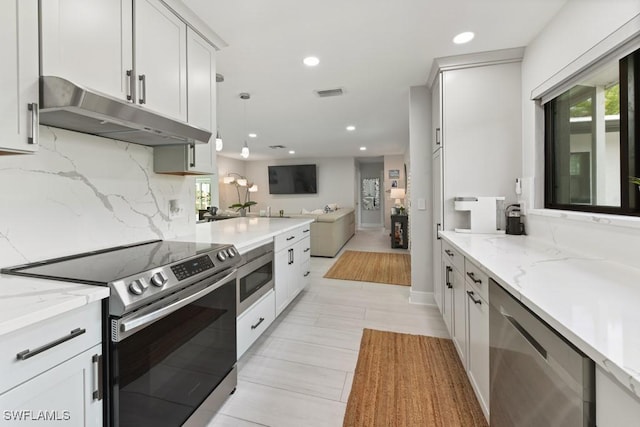 kitchen featuring light stone countertops, hanging light fixtures, appliances with stainless steel finishes, and tasteful backsplash