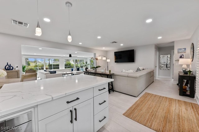 kitchen with decorative light fixtures, white cabinetry, and light stone counters