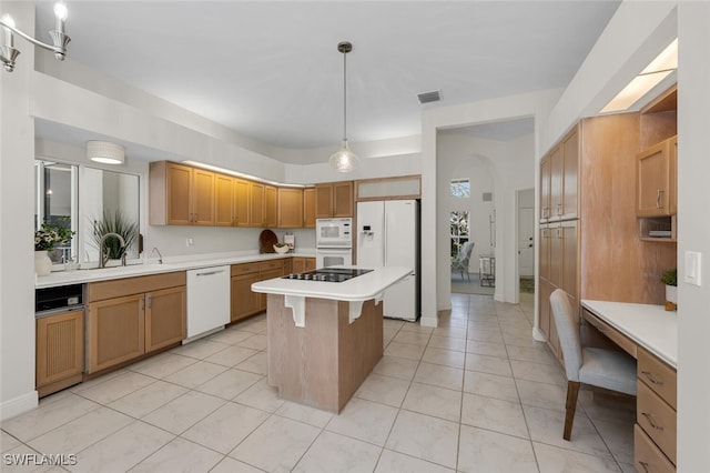 kitchen with pendant lighting, white appliances, a kitchen island, sink, and light tile patterned flooring