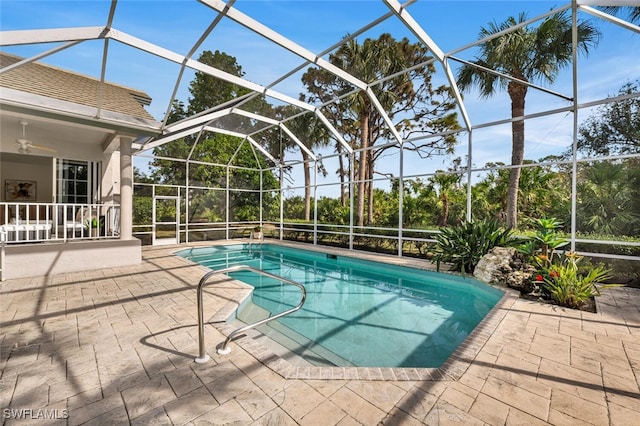 view of swimming pool featuring glass enclosure, a patio area, and ceiling fan