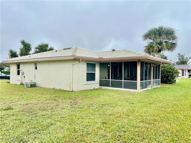 back of house with central AC, a yard, and a sunroom