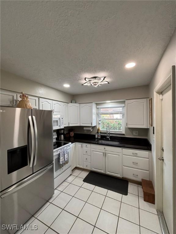 kitchen featuring white cabinetry, sink, white appliances, and a textured ceiling