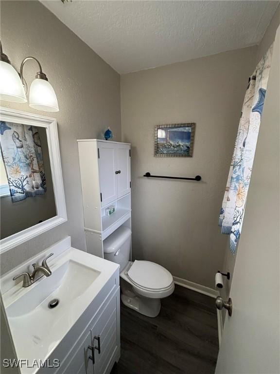 bathroom with hardwood / wood-style flooring, a textured ceiling, toilet, and vanity