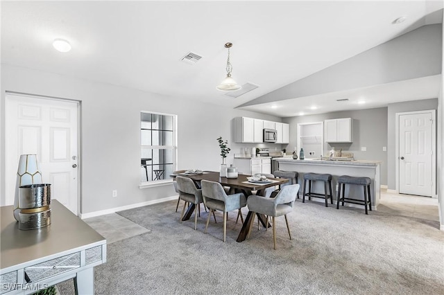 dining room with light colored carpet and vaulted ceiling