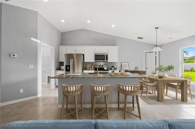 kitchen featuring white cabinets, dark stone countertops, appliances with stainless steel finishes, and light tile patterned flooring