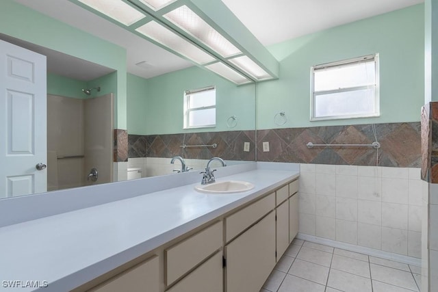 bathroom featuring vanity, tile walls, tile patterned floors, and toilet