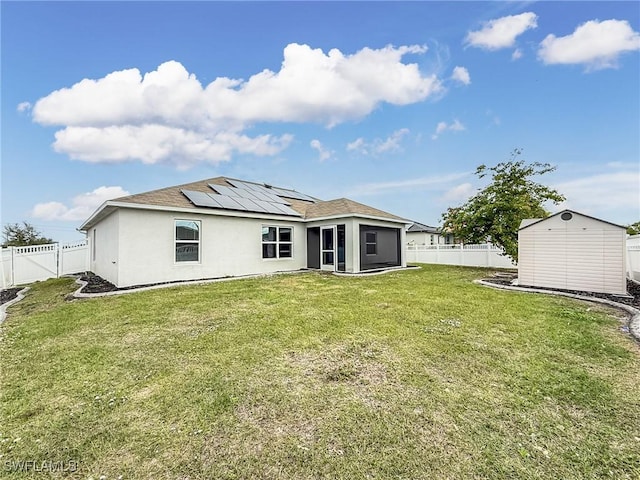 back of house featuring a lawn, a shed, and solar panels