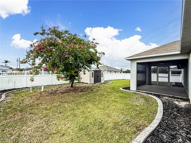 view of yard with a sunroom, a fenced backyard, an outdoor structure, and a storage shed