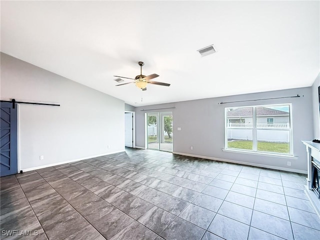 unfurnished room featuring vaulted ceiling, a barn door, and ceiling fan