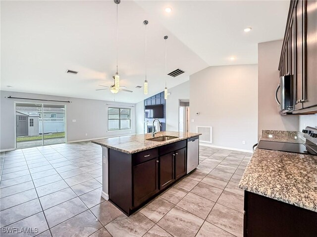 kitchen with hanging light fixtures, stainless steel appliances, sink, and a center island with sink