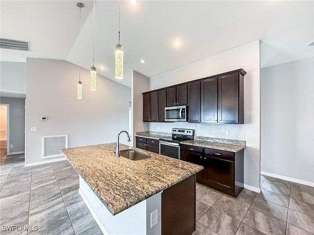 kitchen with pendant lighting, appliances with stainless steel finishes, sink, and an island with sink