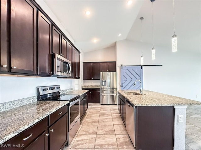 kitchen with appliances with stainless steel finishes, decorative light fixtures, sink, a barn door, and a center island with sink