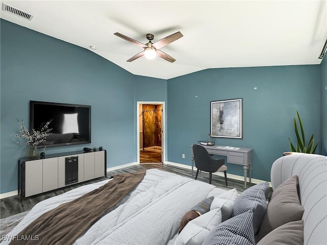 bedroom featuring wood finished floors, visible vents, baseboards, vaulted ceiling, and ensuite bath