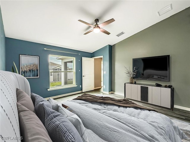 bedroom with lofted ceiling, visible vents, baseboards, and wood finished floors