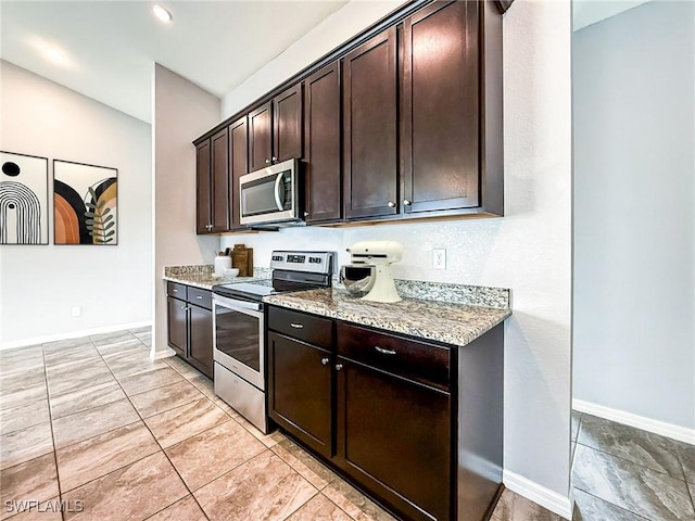 kitchen featuring appliances with stainless steel finishes, baseboards, light stone counters, and dark brown cabinets