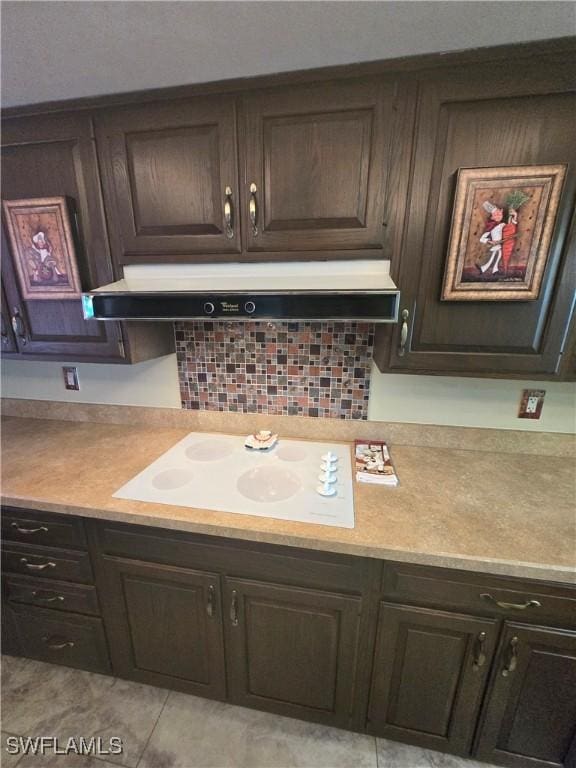 kitchen with dark brown cabinetry, extractor fan, white cooktop, and tasteful backsplash