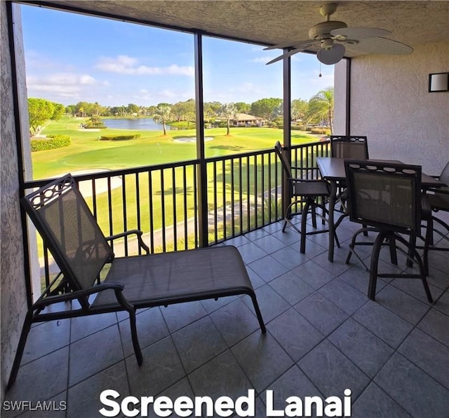 sunroom with a ceiling fan, a water view, and golf course view