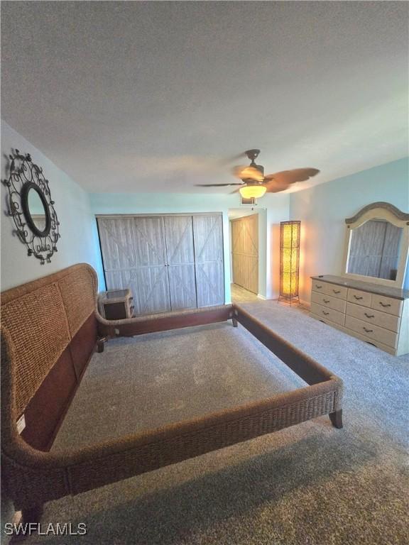 bedroom with ceiling fan, carpet flooring, and a textured ceiling