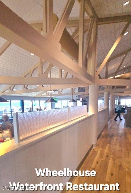 corridor with hardwood / wood-style flooring and high vaulted ceiling