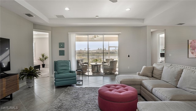 living room with a tray ceiling and light tile patterned flooring