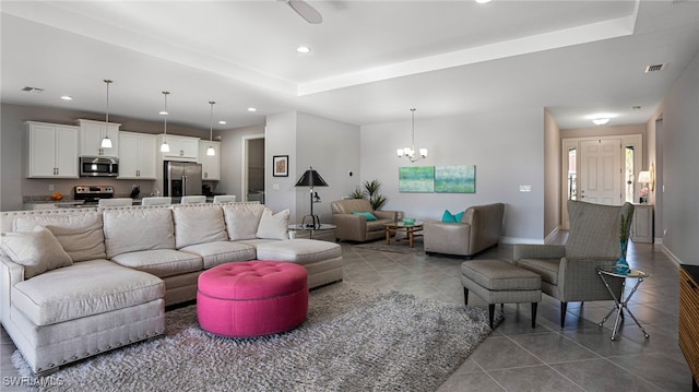 tiled living room featuring an inviting chandelier and a tray ceiling