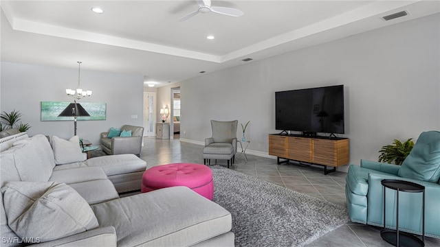 living room featuring ceiling fan with notable chandelier, tile patterned floors, and a raised ceiling