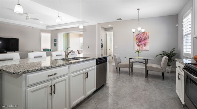 kitchen with sink, decorative light fixtures, appliances with stainless steel finishes, a kitchen island with sink, and white cabinets