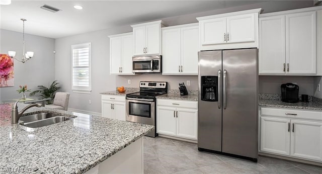 kitchen with light stone counters, stainless steel appliances, sink, and white cabinets