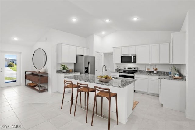 kitchen with an island with sink, white cabinets, stone countertops, and stainless steel appliances