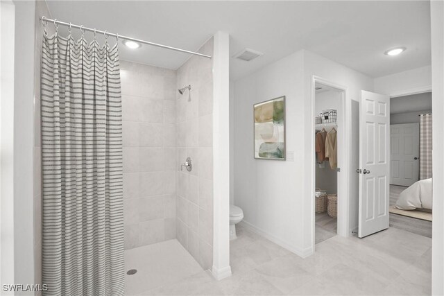 bathroom featuring tiled shower and toilet