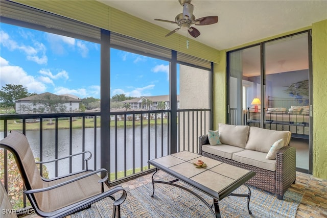 sunroom featuring a ceiling fan and a water view