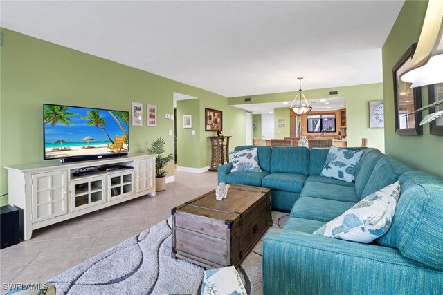 tiled living area featuring visible vents, baseboards, and a notable chandelier