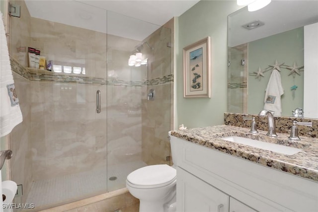 bathroom featuring vanity, toilet, and a shower with shower door